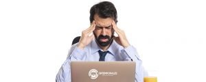 Hombre con dolor de cabeza por estrés laboral frente a su computador