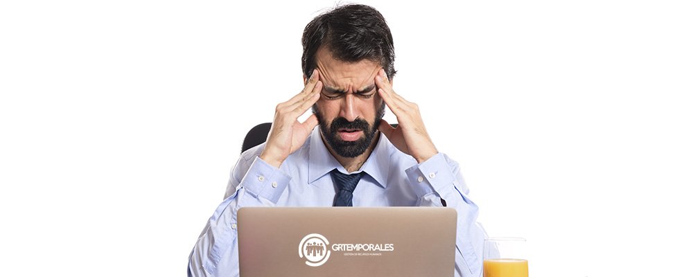 Hombre con dolor de cabeza por estrés laboral frente a su computador