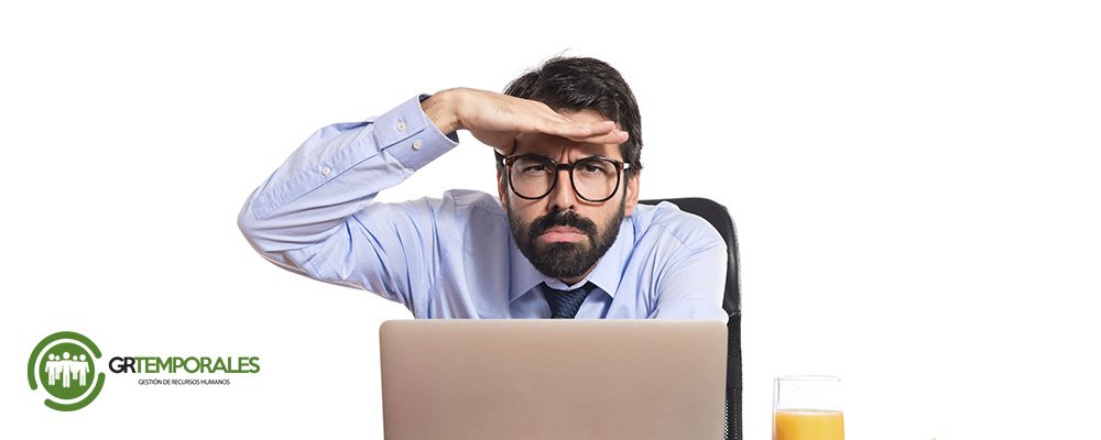 Hombre buscando empleo frente al computador con gesto de duda